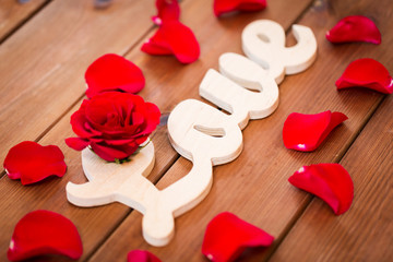 close up of word love cutout with red rose on wood