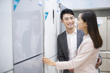 Young couple buying refrigerator in electronics store