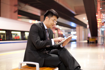 Young businessman using a digital tablet at the train station