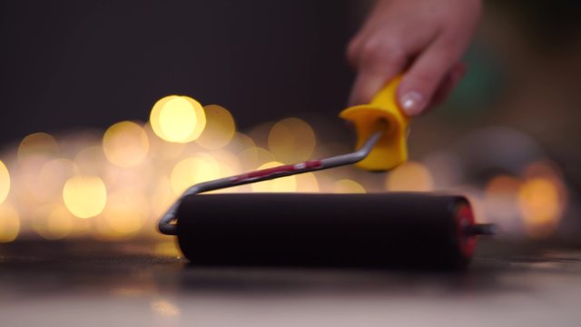 wall in a new building as a background and paint roller in a working position.