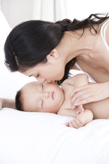 Obraz na płótnie Canvas Mother kissing sleeping baby tenderly