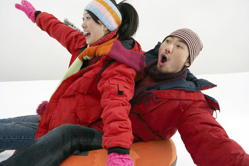 Couple Riding On Inflatable Snow Tube