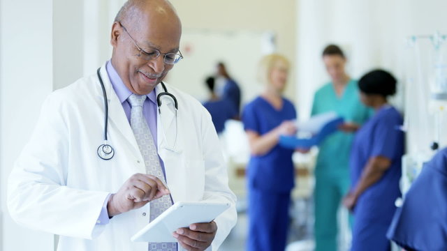 African American male senior staff working on tablet technology in hospital