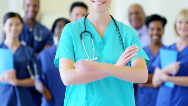 Portrait of confident Caucasian young female nurse and team of staff in hospital