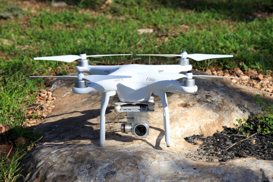Drone equipped with high resolution 4K video camera placed on a green field ready for take off