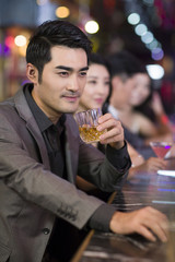 Young man drinking alcohol in bar