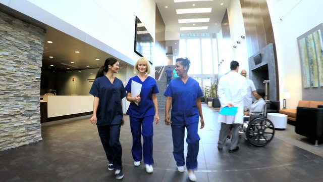 Multi ethnic professional nurses wearing scrubs in hospital entrance