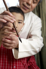 Man Teaching His Grandson The Art Of Calligraphy
