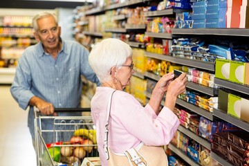 Senior woman taking a picture of product on shelf