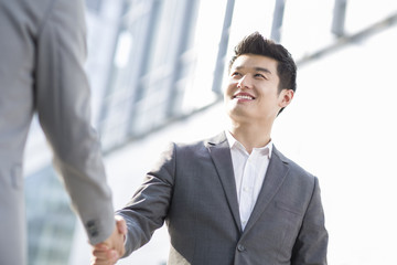 Young business person shaking hands outdoors