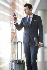 Young businessman using smart phone in airport