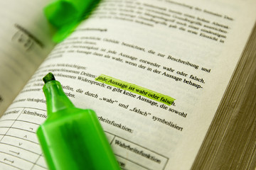 Aufgeschlagenes Buch mit Marker markierter Textstelle 