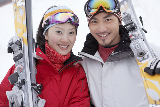 Couple Standing On Ski Field, Holding Skis