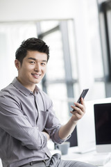 Young businessman using smart phone in office