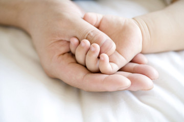 Hand holding infant hand