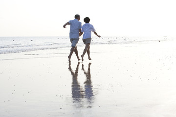 Happy senior couple running on the beach