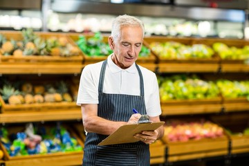Mature worker writing on clipboard
