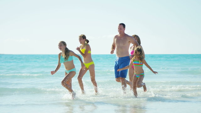 Healthy male female Caucasian family on tropical beach in swimwear