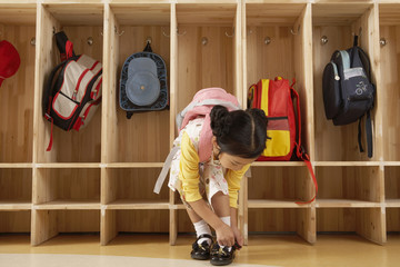 Young Girl Tying Her Shoelaces In Cloak Room