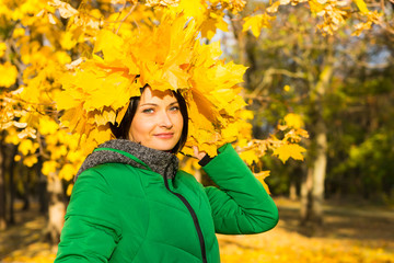 Young woman wearing a hat of yellow autumn leaves