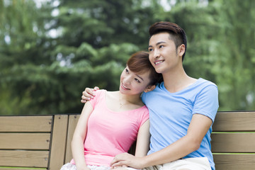 Happy young couple sitting on park bench