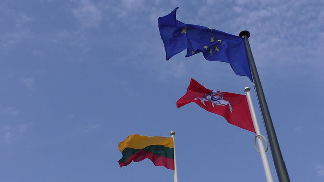Lithuanian national and historical variant state flags and blue European Union EU flag against blue sky close up