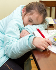 Naklejka premium Young girl falling asleep doing homework
