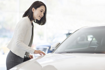 Young woman choosing car in showroom