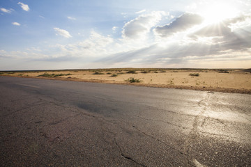 Road going through desert on a clear day in Inner Mongolia province, China