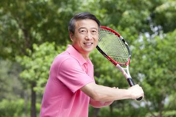 Senior man playing tennis in park