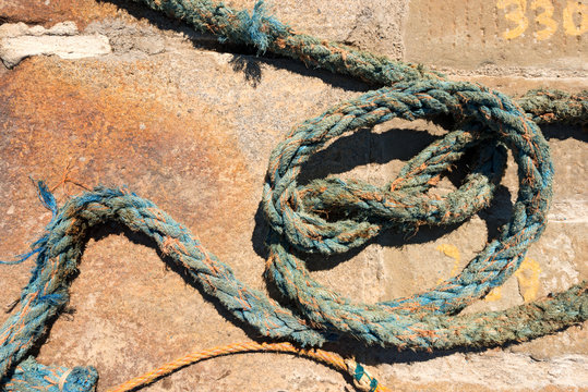 Weathered Nautical Rope on a Pier / Detail of weathered nautical rope, blue and orange, on the pier in the harbor
