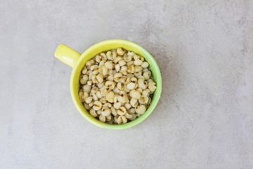 Job's tears boiled grains with syrup in Green cup for health on gray tile surface  (thai dessert...