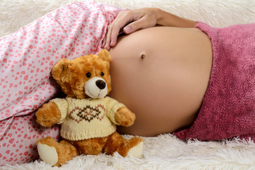 Close-up of a pregnant belly and toy bear