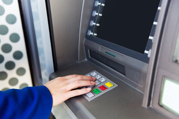 close up of hand entering pin code at cash machine