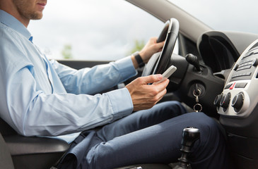 close up of man with smartphone driving car