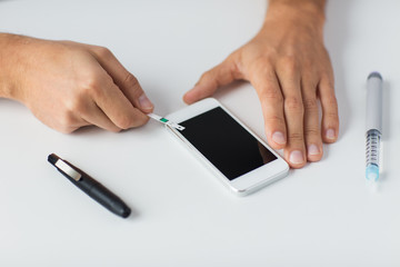 close up of man with smartphone making blood test