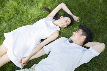 Happy young couple lying on grass