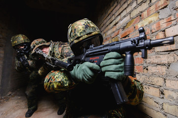 Fototapeta premium Three men in uniform with guns in dark room/Close up of three elite police marksmen in German uniform with weapon in dark room