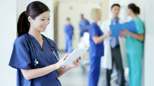 Chinese American female young nurse working on tablet technology in hospital