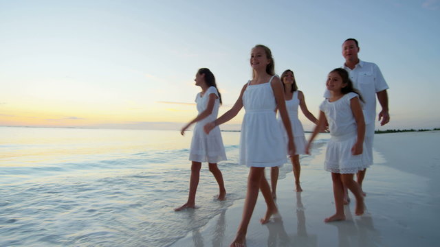 Barefoot Caucasian family wearing white clothes on the beach 