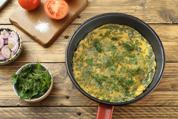 vista dall'alto frittata  uova di gallina con erbe in padella di metallo sfondo rustico 
