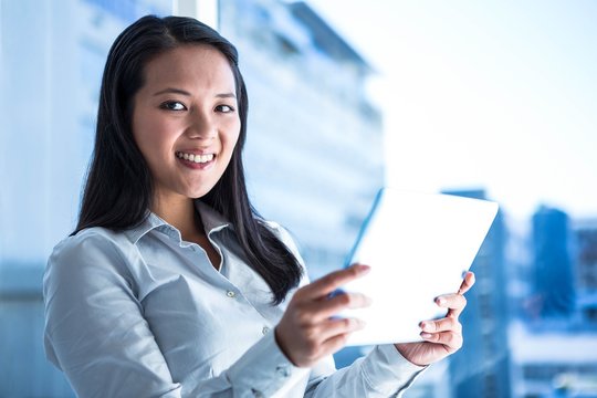 Smiling businesswoman holding tablet and looking at camera
