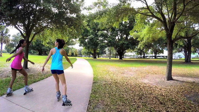 Young slim multi ethnic females inline skating in park