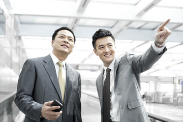 Chinese business people looking at view in airport lobby