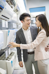 Young couple buying air conditioner in electronics store