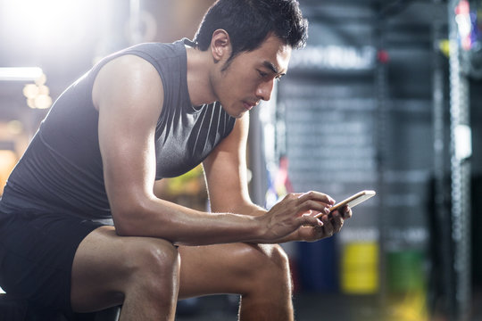 Young man using smartphone in gym