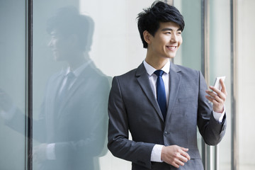 Fototapeta premium Young businessman holding mobile phone