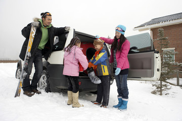 Family Unloading Car On Ski Field 