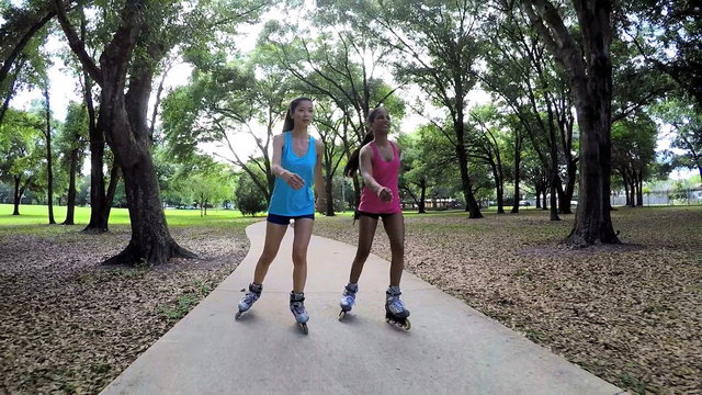 Young slim multi ethnic females inline skating in park