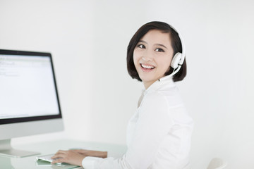 Cheerful businesswoman with headset in office